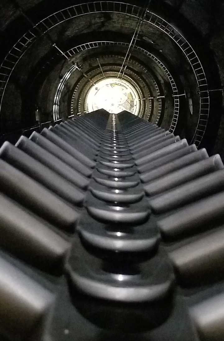 View from the top of the shaft, showing the staircase at the edge and the gear wheels in the centre.