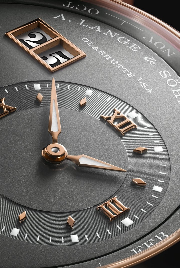 Close-up of the Lange 1 Perpetual Calendar in rose gold with a grained grey dial. Hands, indices and the double window for the outside date are also in rose gold.